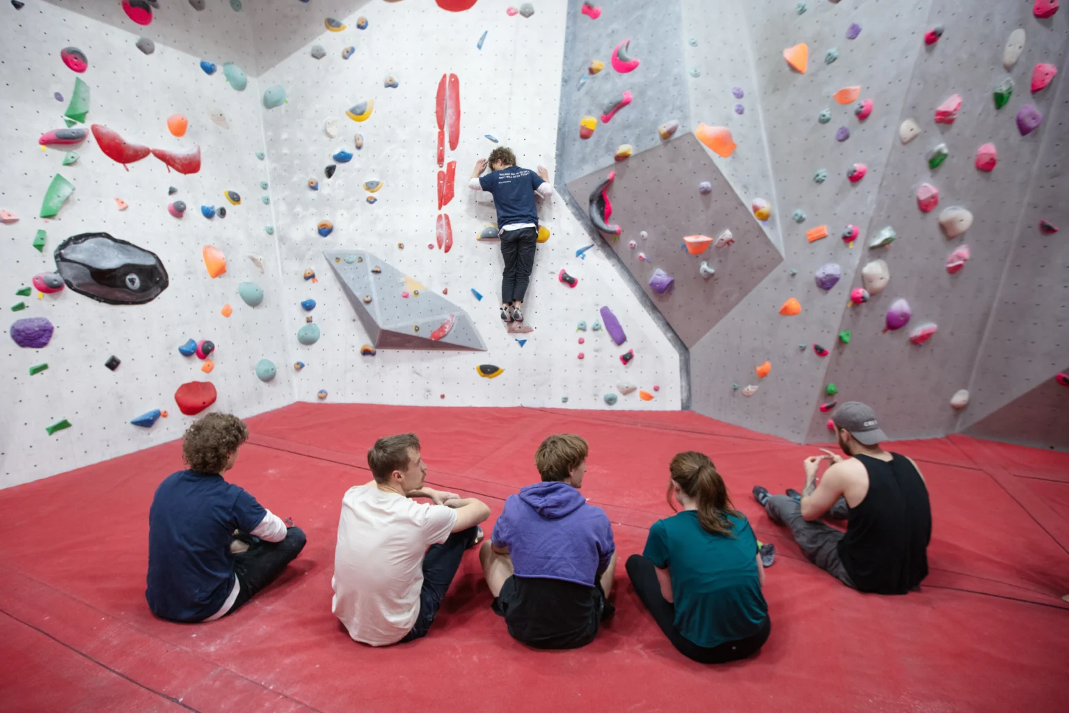 A group of boulderers looking at a climber on the wall